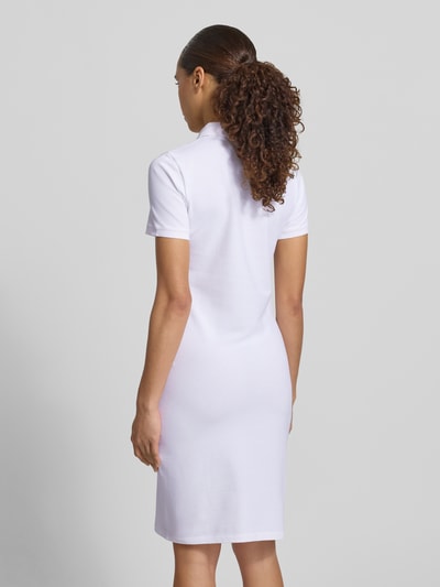 Vrouwenmodel draagt Knielanges Polokleid met Label-Stitching van Gant in wit, mix van katoen en elastaan, recht model, knielengte, knoopsluiting, ruglengte maat S 95 cm, borstwijdte 41 cm, mouwlengte 20 cm, volledige lichaamsopname achteraan.