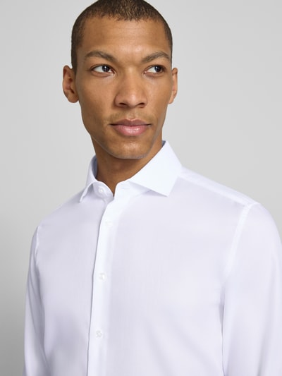 Männermodel trägt weißes Slim Fit Business-Hemd aus Baumwolle mit Kentkragen von SEIDENSTICKER, fein strukturiert, Nahaufnahme Oberkörper.