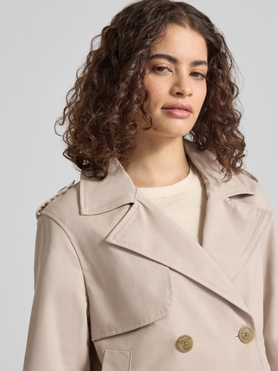 Kobieta modelka nosi Regular Fit Trenchcoat mit Umlegekragen od Review w kolorze beżowym, czysta bawełna, dwurzędowy, kieszenie, szerokość ramion w rozmiarze S 45 cm, szerokość biustu w rozmiarze S 53 cm, długość rękawa w rozmiarze S 62 cm, długość pleców w rozmiarze S 55 cm, zbliżenie na górną część ciała.