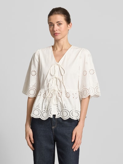 Vrouwenmodel draagt Regular Fit blouse met ajourwerk model 'Cornelia' van YAS, V-hals, halflange mouwen, sierstrikken, ruglengte maat 36: 56 cm, mouwlengte maat 36: 37 cm, kleur wit, organische vormen, textuur door ajourwerk, voorkant volledig zichtbaar, Ganzkörperansicht von voren.