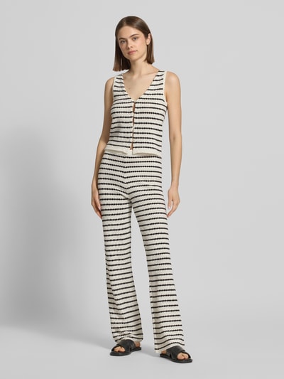 Frauenmodel trägt Strickweste mit V-Ausschnitt und Knopfleiste von REVIEW im Allover-Look, Material-Mix mit Baumwoll-Anteil, Regular-Fit, creme und schwarz, Ganzkörperansicht von vorne.
