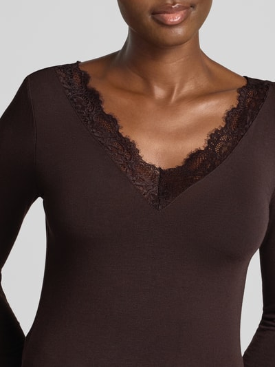 Kobieta nosi ciemnobrązową bluzkę z długim rękawem z koronką przy dekolcie, Slim Fit Langarmshirt aus Modal-Mix mit Woll-Anteil Modell 'SKYE' od VERO MODA, damska bluzka z długim rękawem, zbliżenie na górną część ciała