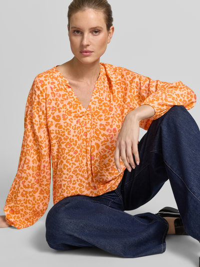 Frauenmodel trägt Damenbluse im Allover-Look mit V-Ausschnitt von Emily Van den Bergh in Orange-Rosa, reine Viskose, Nahaufnahme Oberkörper.