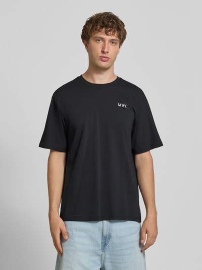 Męski model nosi czarny t-shirt Relaxed Fit T-Shirt aus reiner Baumwolle Modell 'CAP' von ONLY, jednolita faktura, Ganzkörperansicht von vorne.