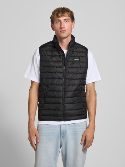 Männermodel trägt Steppweste mit Reißverschlusstaschen Modell 'ELVIS' von JACK & JONES, schwarz, strukturierte Oberfläche, Ganzkörperansicht von vorne