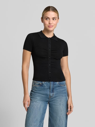 Frauenmodel trägt Slim Fit Cardigan mit Woll-Anteil von MANGO, schwarz, kurzärmelig, Knopfleiste, Umlegekragen, glatte Textur, Ganzkörperansicht von vorne.