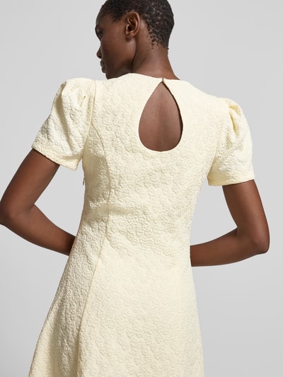 Frauenmodel trägt Midikleid mit floralem Allover-Detail von ROTATE, Elastischer-Material-Mix, A-Linie, kurzärmelig, Struktur, Ganzkörperansicht Rückansicht.