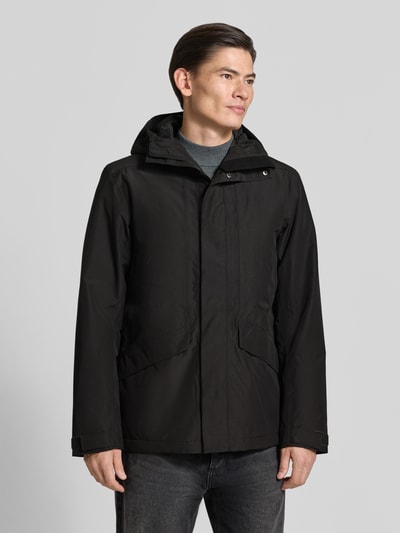 Männermodel trägt Regular Fit Jacke mit Kapuze Modell 'Adam' von Didriksons, schwarze Farbe, Eingrifftaschen, Ganzkörperansicht von vorne. Rückenlänge, Schulterbreite, Brustweite und Ärmellänge bei Größe M: 79/46/58/73 cm.