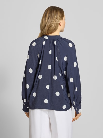 Frauenmodel trägt Bluse aus Viskose-Mix mit Serafino-Ausschnitt von Christian Berg Woman, dunkelblau mit weißen Punkten, Loose-Fit, verlängerter Rücken, Damen Bluse, Rückenlänge 61 cm, Ärmellänge 60 cm, Ganzkörperansicht Rückansicht.