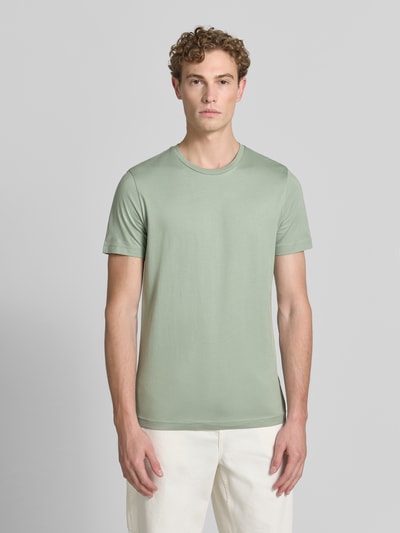 Męski model nosi T-Shirt aus Baumwolle mit Rundhalsausschnitt von Christian Berg Men, krój slim fit, bawełna, okrągły dekolt, długość tyłu w rozmiarze m: 73 cm, jasna zieleń, gładka faktura, pełny widok z przodu.