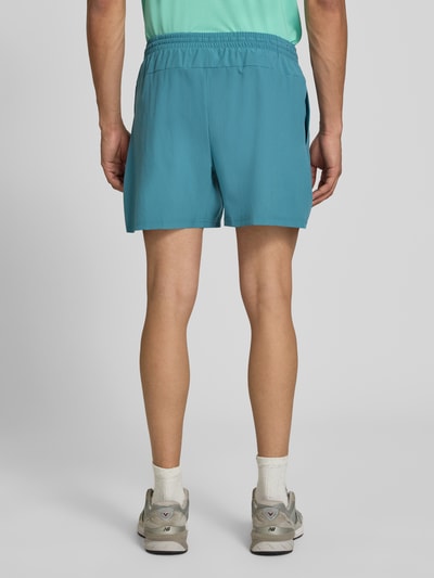 Männermodel trägt Shorts mit elastischem Bund und Logo von New Balance in Blau, Regular Fit, Ganzkörperansicht Rückansicht.