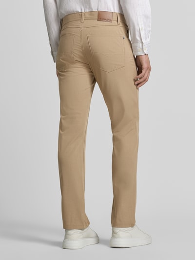 Męski model nosi Comfort Fit Hose mit Eingrifftaschen von Christian Berg Men, beżowe spodnie, mieszanka materiałów z dodatkiem wiskozy, wpuszczane kieszenie, kieszenie z tyłu, szerokość w rozmiarze 32/32: 41 cm, długość wewnętrzna nogawki: 78 cm, całkowity widok z tyłu.