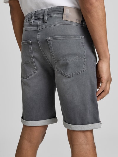 Männermodel trägt Bermudas in Denim-Optik von MAC, Used-Look, Umschlag, Eingrifftaschen, graue Farbe, Ganzkörperansicht Rückansicht.