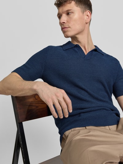 Männermodel trägt Slim Fit Poloshirt mit V-Ausschnitt von GRAN SASSO aus Flachs-Baumwoll-Mix in Blau, Nahaufnahme Oberkörper.
