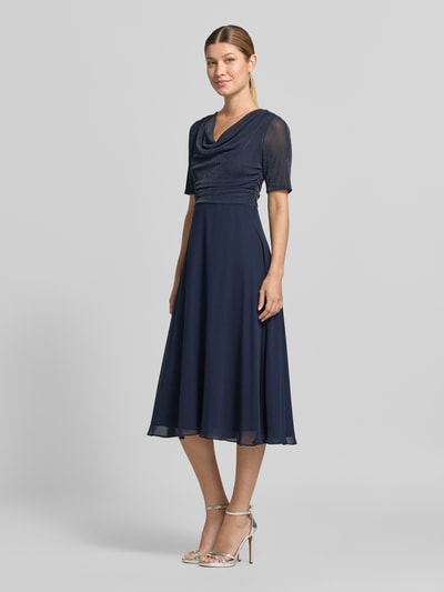 Kobiece model prezentuje Fit and Flare Cocktailkleid mit Wasserfallausschnitt od Vera Mont, granatowa, lekko połyskujący materiał, długość midi, całkowity widok z przodu