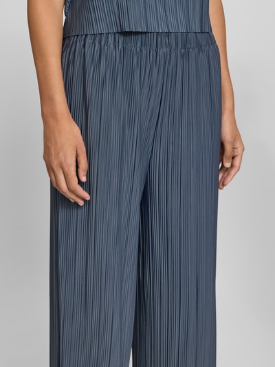 Frauenmodel trägt Wide Fit Stoffhose in Plissee-Optik Modell 'Uma' von Samsøe Samsøe in blauem Elastischer-Material-Mix, Nahaufnahme Oberkörper, Damen Stoffhose, Elastischer Bund, Bundweite 32 cm, Innenbeinlänge 74 cm.