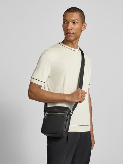 Mannenmodel draagt schoudertas met logo-applicatie van BOSS in look: effen kleuren met ritssluiting, schouderband, rechthoekig model. Ganzkörperansicht van voren.