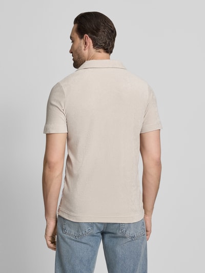 Männermodel trägt Relaxed Fit Poloshirt mit V-Ausschnitt von Lindbergh aus Baumwoll-Mix Frottee in Beige, Brusttasche, Rückenlänge 76 cm, Ganzkörperansicht Rückansicht.
