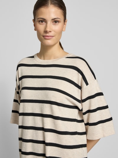 Frauenmodel trägt Strickshirt aus Viskose-Mix Modell 'Conny' von FREE/QUENT, beige mit schwarzen Streifen, Nahaufnahme Oberkörper. Relaxed Fit, Rundhalsausschnitt, 3/4-Arm, Rückenlänge 57 cm, Ärmellänge 26 cm, feine glatte Textur.
