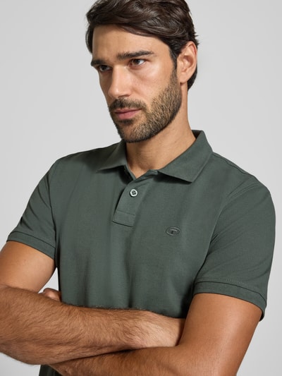 Męski model nosi Regular Fit Poloshirt aus Baumwoll-Mix von Tom Tailor w kolorze ciemnej zieleni, widok z przodu, zbliżenie na górną część ciała.