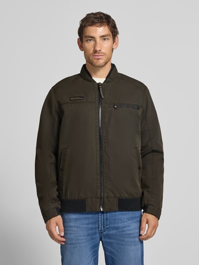 Männermodel trägt Blouson mit Stehkragen und Eingrifftaschen von camel active in Dunkelgrün, sichtbare Reißverschlusstasche, Ganzkörperansicht von vorne. Regular Fit, Label-Detail, strukturierte Oberfläche, Kontrastdetails, Kontext: Herren Blouson, Rückenlänge 68 cm, Schulterbreite 43 cm, Brustweite 60 cm, Ärmellänge 65 cm.