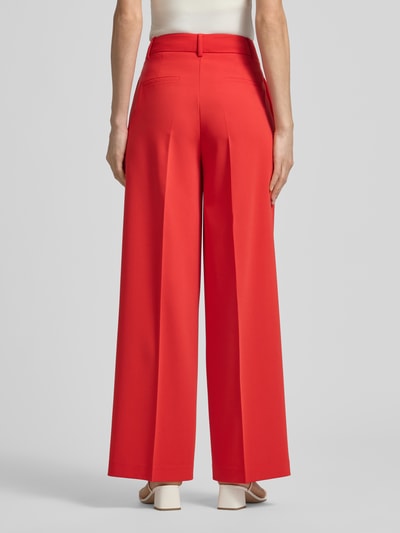 Frauenmodel trägt rote Hose mit Bügelfalten von More & More, Material-Mix mit Viskose-Anteil, Regular-Fit, Gesäßtaschen, Ganzkörperansicht Rückansicht.