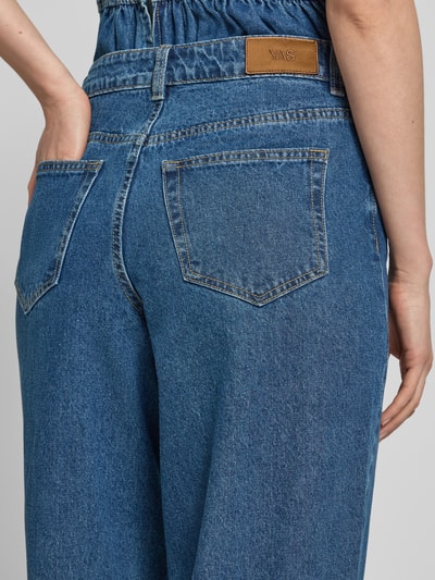 Frauenmodel trägt Wide Fit Jeans mit Ziernähten Modell 'Elsie' von YAS, blaue Denimstruktur, 5-Pocket-Design, Ganzkörperansicht Rückansicht, Knopf- und Reißverschluss, Bundweite bei Größe 27/32: 37 cm, Innenbeinlänge: 83 cm.