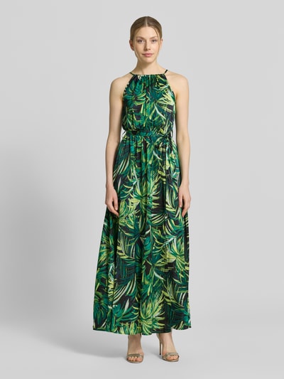 Frauenmodel trägt Maxikleid mit Bindegürtel von Apricot im Allover-Look mit grünen und gelben Blattmotiven, A-Linie, Ganzkörperansicht von vorne.