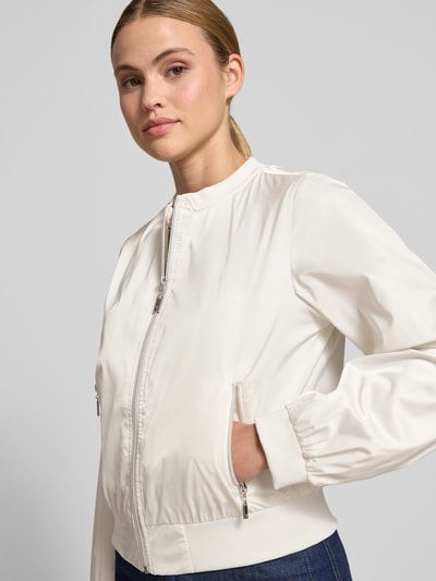 Frauenmodel trägt Jacke mit Rundhalsausschnitt und Reißverschlusstaschen von monari in Weiß, Regular-Fit, glatte Struktur, Nahaufnahme Oberkörper. Rückenlänge bei Größe 36: 52 cm, Schulterbreite: 46 cm, Brustweite: 53 cm, Ärmellänge: 57 cm.