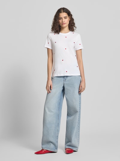 Frauenmodel trägt Regular Fit T-Shirt aus reiner Bio-Baumwolle Modell 'KETTY LIFE' von Only, weiß mit roten Stickereien, unifarben, Rundhals, kurzarm, Ganzkörperansicht von vorne.