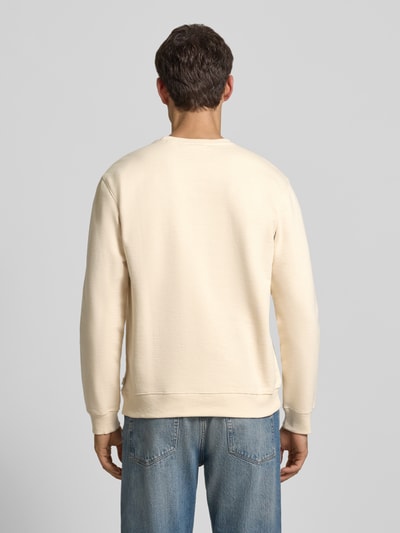 Männermodel trägt Sweatshirt mit Label-Print van Scotch & Soda in beige, rechte vormen, katoen, regular fit, ribboorden, rugaanzicht, ruglengte 67 cm, mouwlengte 63 cm.