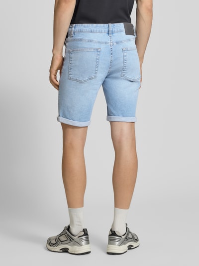 Męski model nosi szorty jeansowe z mieszanki bawełny, model 'PLY' marki, krój regular fit, denim, naszywka z logo, 5 kieszeni, brzeg z mankietem, szlufki na pasek, widok całej sylwetki z tyłu.