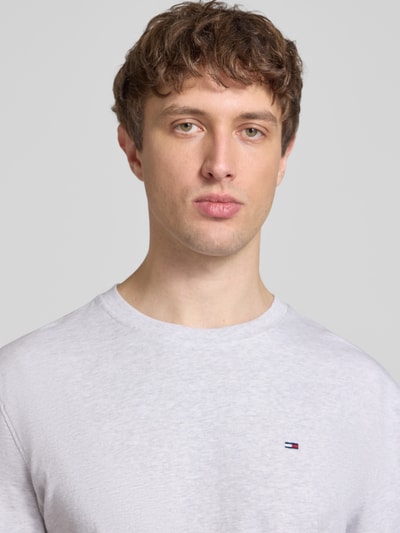 Männermodel trägt Regular Fit T-Shirt aus reiner Baumwolle von Tommy Jeans, weiß, Logo-Stitching, Nahaufnahme Oberkörper.