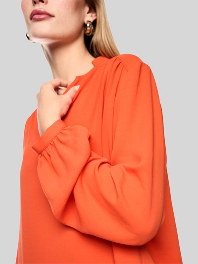 Vrouwenmodel draagt Regular fit blouse met v-hals en opstaande kraag van Marc Cain, plooien, oranje, dames blouse, detailopname bovenlichaam. Ruglengte bij maat 36: 63 cm, mouwlengte bij maat 36: 65 cm.