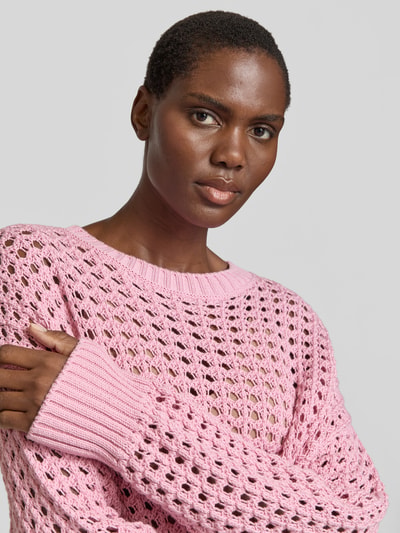 Vrouwenmodel draagt Relaxed Fit Pullover mit Lochmuster van Juvia in roze katoen met rond hals, elastische boorden, maat S ruglengte 58 cm, close-up bovenlichaam.