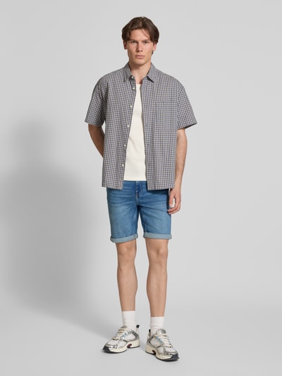 Männermodel trägt Regular Fit Jeansshorts aus Baumwoll-Mix Modell 'PLY' von Only & Sons in Denim-Optik mit Label-Patch, Gürtelschlaufen, Beinabschluss mit Umschlag und 5-Pocket-Design, Ganzkörperansicht von vorne.