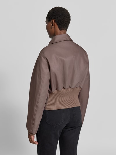 Frauenmodel trägt Jacke aus reiner Baumwolle von Victoria Beckham in Braun, Stehkragen, elastische Ärmelabschlüsse, Ganzkörperansicht Rückansicht.