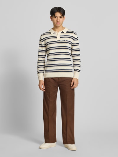 Männermodel trägt Loose Straight Fit Hose mit Bügelfalten von Dickies in Braun, Baumwoll-Mix, Eingrifftaschen, Ganzkörperansicht von vorne.