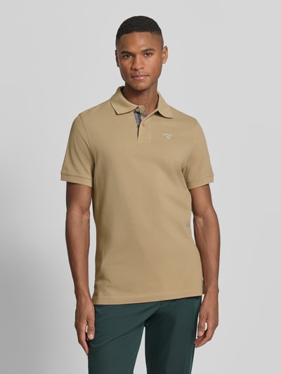 Männermodel trägt Regular Fit Poloshirt aus reiner Baumwolle von Barbour, Optik: Unifarben, Label-Stitching-Applikation, Piqué, Ganzkörperansicht von vorne.