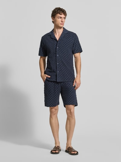 Männermodel trägt Regular Fit Shorts mit Label-Patch von Lindbergh aus Baumwoll-Mix mit Eingrifftaschen und Gesäßtasche, Ganzkörperansicht von vorne.