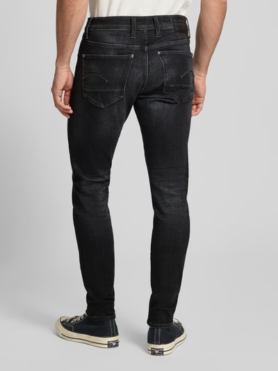 Männermodel trägt Skinny Fit Jeans mit 5-Pocket-Design von G-Star Raw, ciemny jeans, dopasowany krój, widok na całe ciało od tyłu.