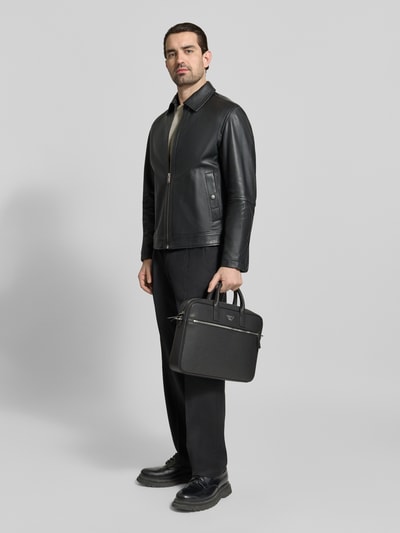 Männermodel trägt Laptoptasche mit Label-Detail und Schulterriemen von Emporio Armani in Schwarz, Ganzkörperansicht von vorne. Hauptfach mit Reißverschluss, Außenfach und langer Schulterriemen, glatte Struktur, dezentes Branding.