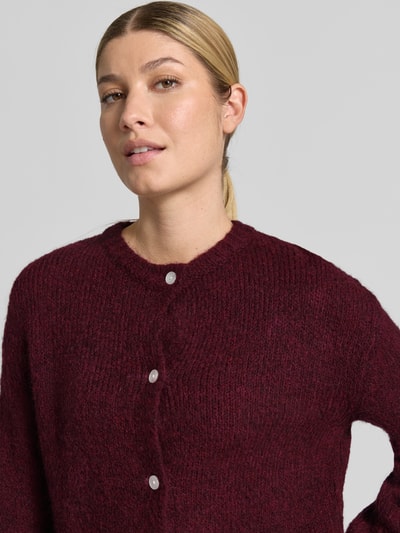 Frauenmodel trägt bordeauxroten Cardigan mit Alpaka-Anteil und Rundhalsausschnitt Modell 'OTIA' von b.young, Knopfleiste, Nahaufnahme Oberkörper.