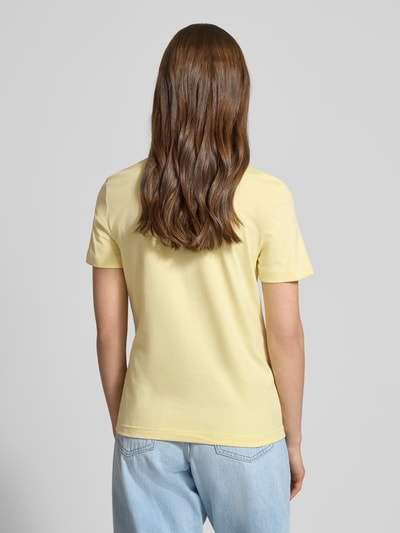 Kobiece modelka nosi T-Shirt mit Rundhalsausschnitt und Label-Stitching od Calvin Klein Jeans, czysta bawełna, krój regular fit, długość tyłu w rozmiarze S: 52 cm, jasny żółty kolor, prosta forma, gładka tekstura, widok całej sylwetki od tyłu