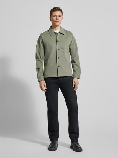 Męskamodel nosi Relaxed Fit Hemdjacke mit Brusttasche von Lindbergh, mieszanka materiałów z dodatkiem wiskozy, wykładany kołnierz, brustasza, listwa guzikowa, kolor zielony, długość tyłu w rozmiarze M: 69 cm, całkowity widok z przodu.