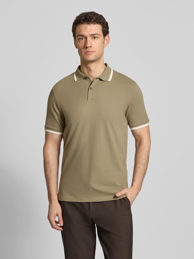 Männermodel trägt Slim Fit Poloshirt aus Bio-Baumwoll-Mix Modell 'SLIM ATLAS SPORT' von SELECTED HOMME in Beige mit Kontraststreifen, Piqué-Struktur, unifarben, Ganzkörperansicht von vorne.
