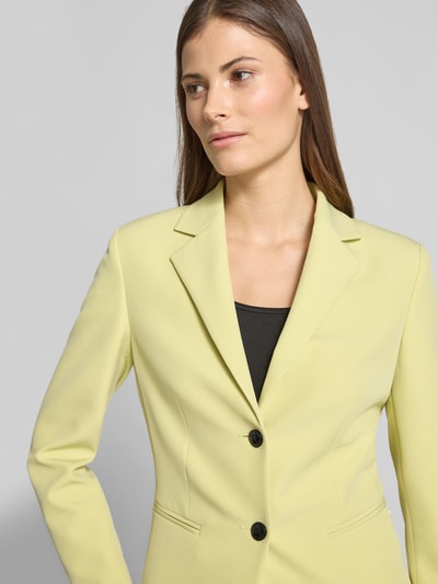 Vrouwenmodel draagt Slim Fit Kurzblazer met Logo-Applikation Modell 'Agonia-1' van HUGO in effen lichtgeel, twill, knoopsluiting, paspelzakken, reverskraag, detailopname bovenlichaam