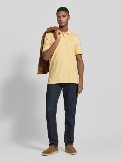 Männermodel trägt Regular Fit Poloshirt mit Logo-Stitching von Fynch-Hatton in Gelb, reine Baumwolle, Polokragen, Ganzkörperansicht von vorne.