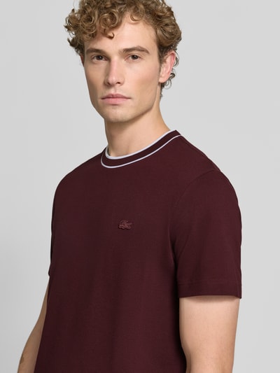 Mannenmodel draagt regular fit t-shirt uit katoenmix van Lacoste in donkerrood met fijne textuur, Nahaufnahme bovenlichaam.