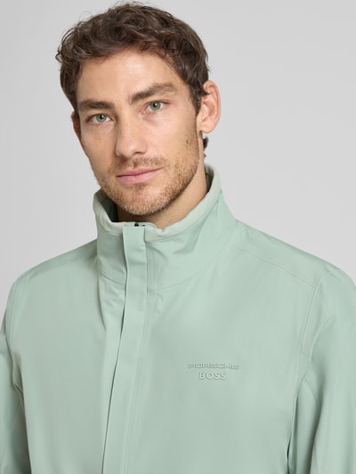 Männermodel trägt Regular Fit Funktionsjacke aus wasserdichtem Material - Porsche x BOSS, Optik: Unifarben, Label-Print, Nahaufnahme Oberkörper.